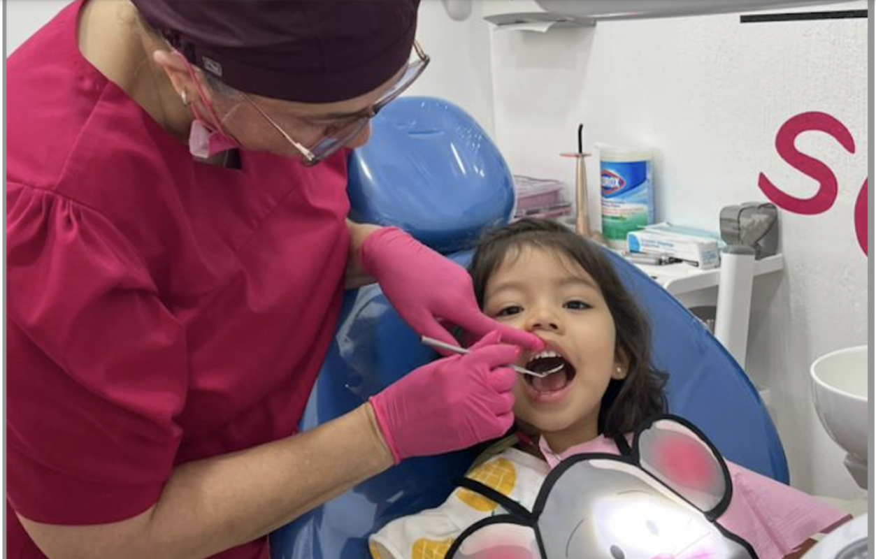 Odontopediatra revisando los dientes de una niña en consulta dental infantil