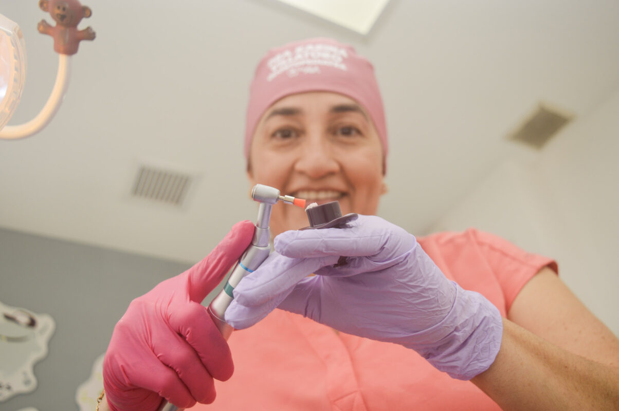 Odontopediatra utilizando equipo dental en consulta infantil con enfoque amigable