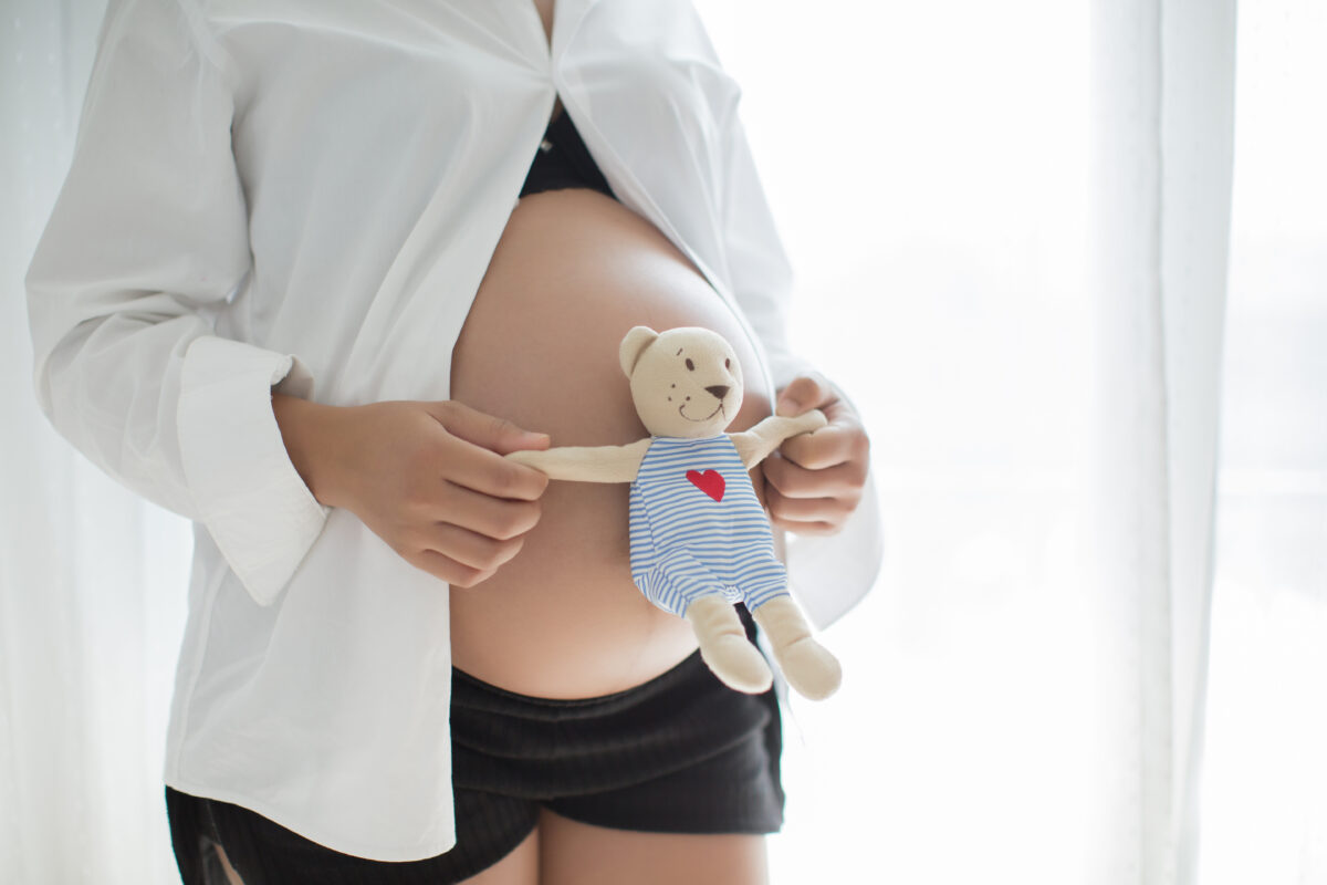 Mujer embarazada sosteniendo un peluche sobre su vientre, cuidado prenatal y salud del bebé